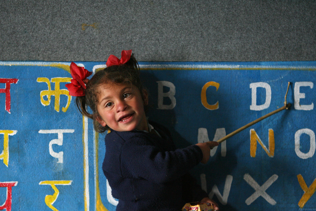 Image description. Little girl at Shreeshitalacom Lower Secondary School leads her class in pronunciation of the English alphabet in Kaski, Nepal