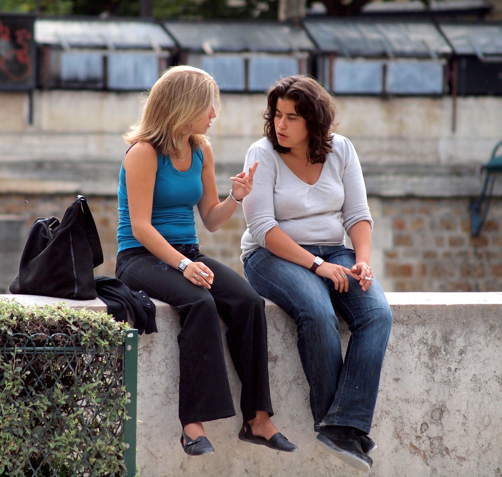 Two friends sitting on a wall and chatting